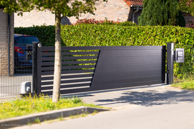 Portail coulissant motorisé en aluminium sur-mesure Création de couleur noir, installé devant une maison