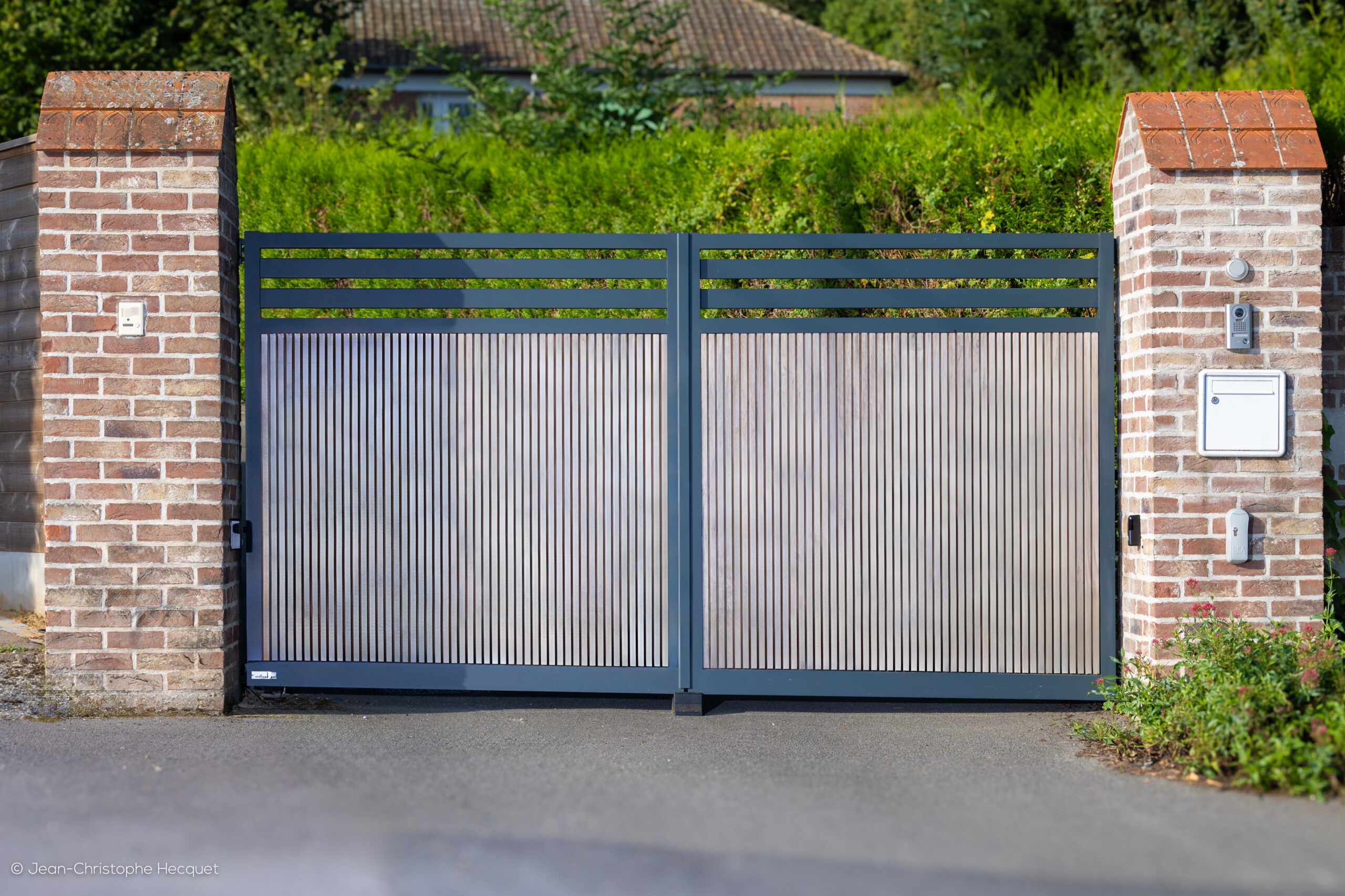 Portail battant en aluminium et bois sur-mesure Dixie de couleur gris anthracite, installé devant une maison