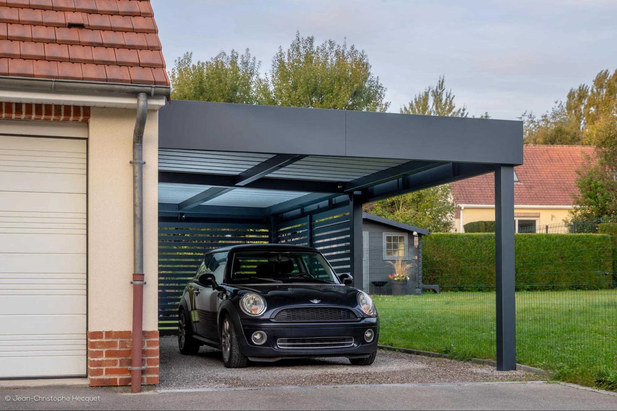 Carport adossé ORION avec voiture stationnée, bandeau Horizon laqué 7016, brise vue Bellerive ajourés, installation à Bondues (59910)