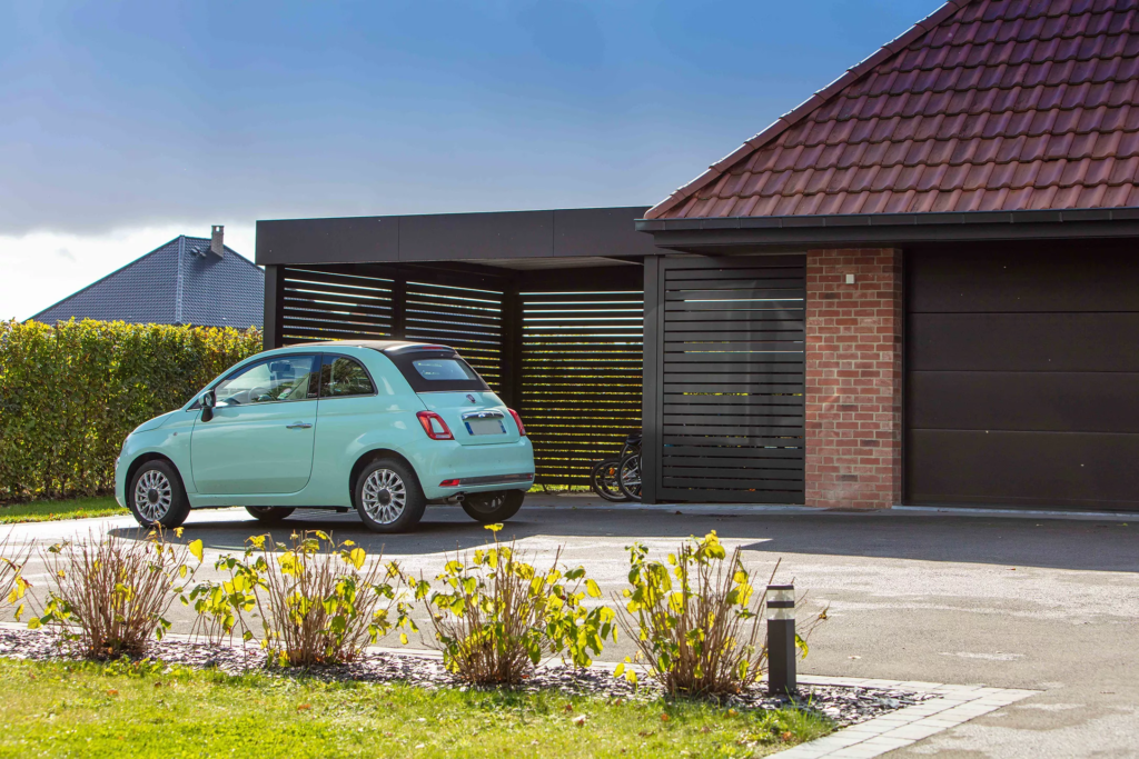 Installation d’un carport ORION autoporté en aluminium laqué RAL 9005 avec brise-vue ajouré modèle Bellerive et bandeau HORIZON à découpe architecturale – Laventie