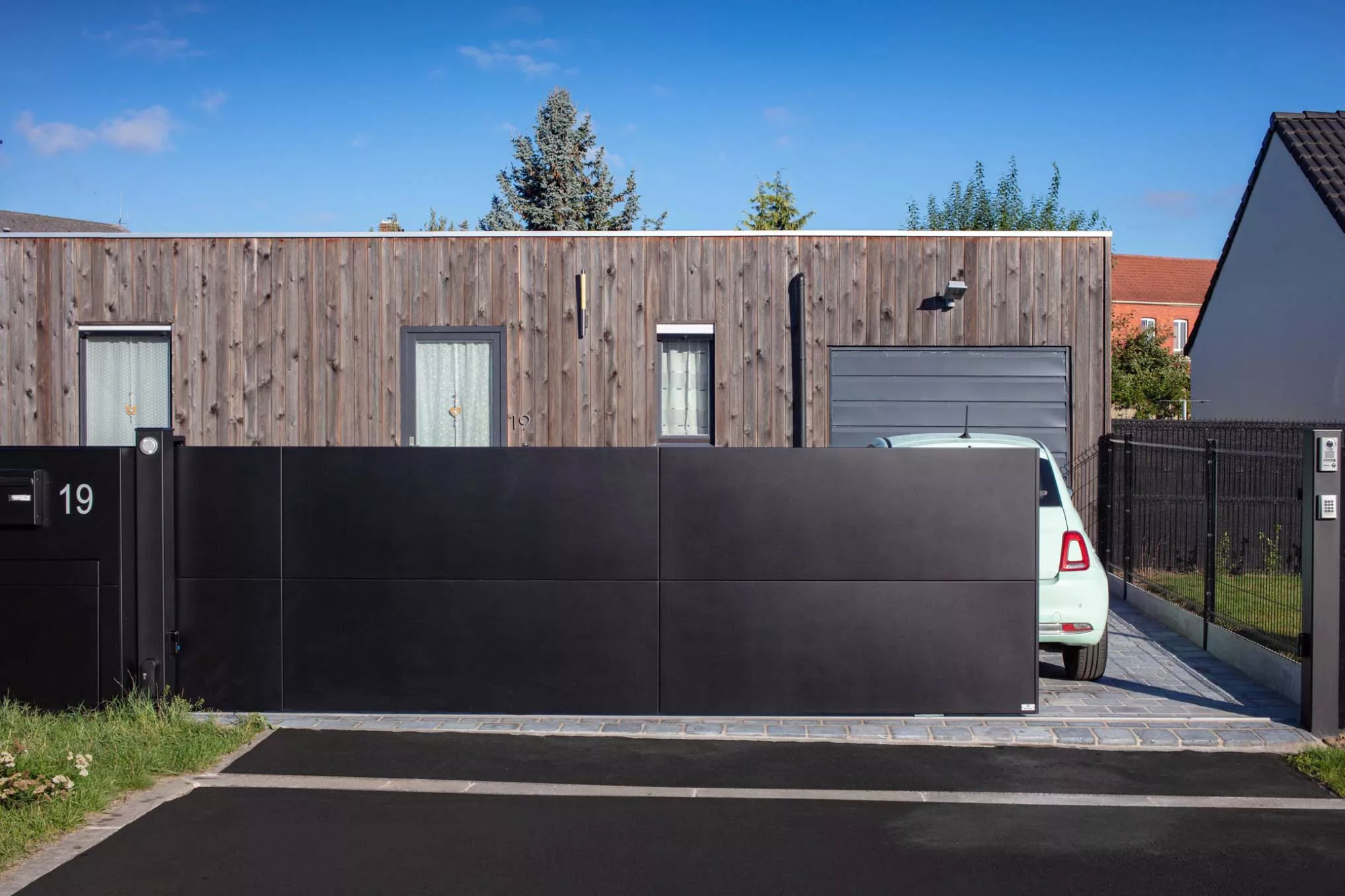 Vue extérieure d’un portail plein noir avec numéro découpé, modèle Horizon à Carvin