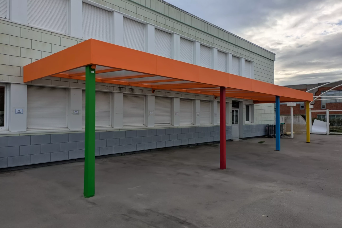 Préau aluminium sur mesure installé à Oye-Plage avec toiture translucide et poteaux colorés