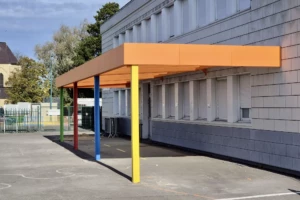 Préau aluminium adossé multicolore avec toiture polycarbonate à l’école des Dunes d’Oye-Plage