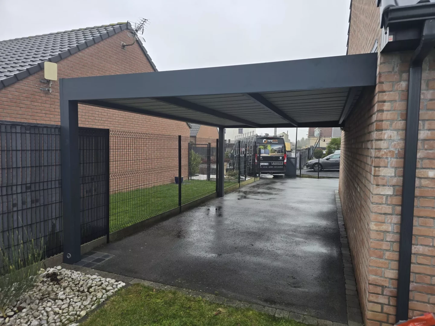 Carport aluminium adossé gris anthracite installé par Newtech Fermetures pour protéger une allée de stationnement extérieure