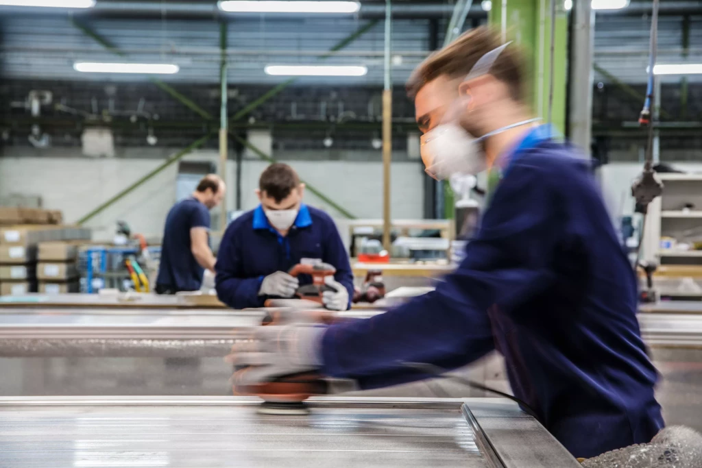 Ponçage d'un profilé aluminium en atelier lors de la fabrication d'un portail sur mesure à Fretin