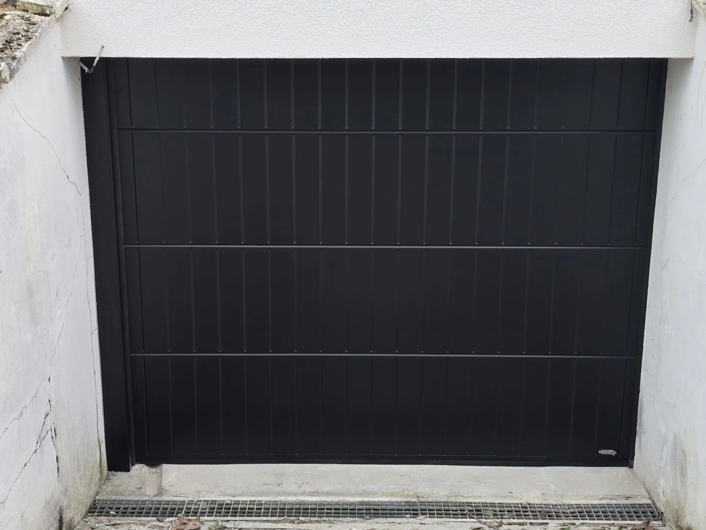 Vue de face d’une porte de garage sectionnelle noire installée à Bondues
