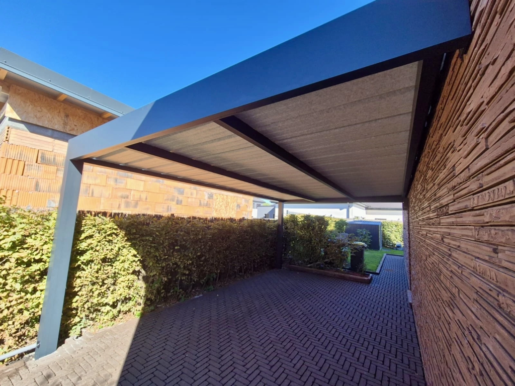 Carport adossé aluminium gris anthracite à toiture plate au-dessus d’une allée pavée à Mérignies